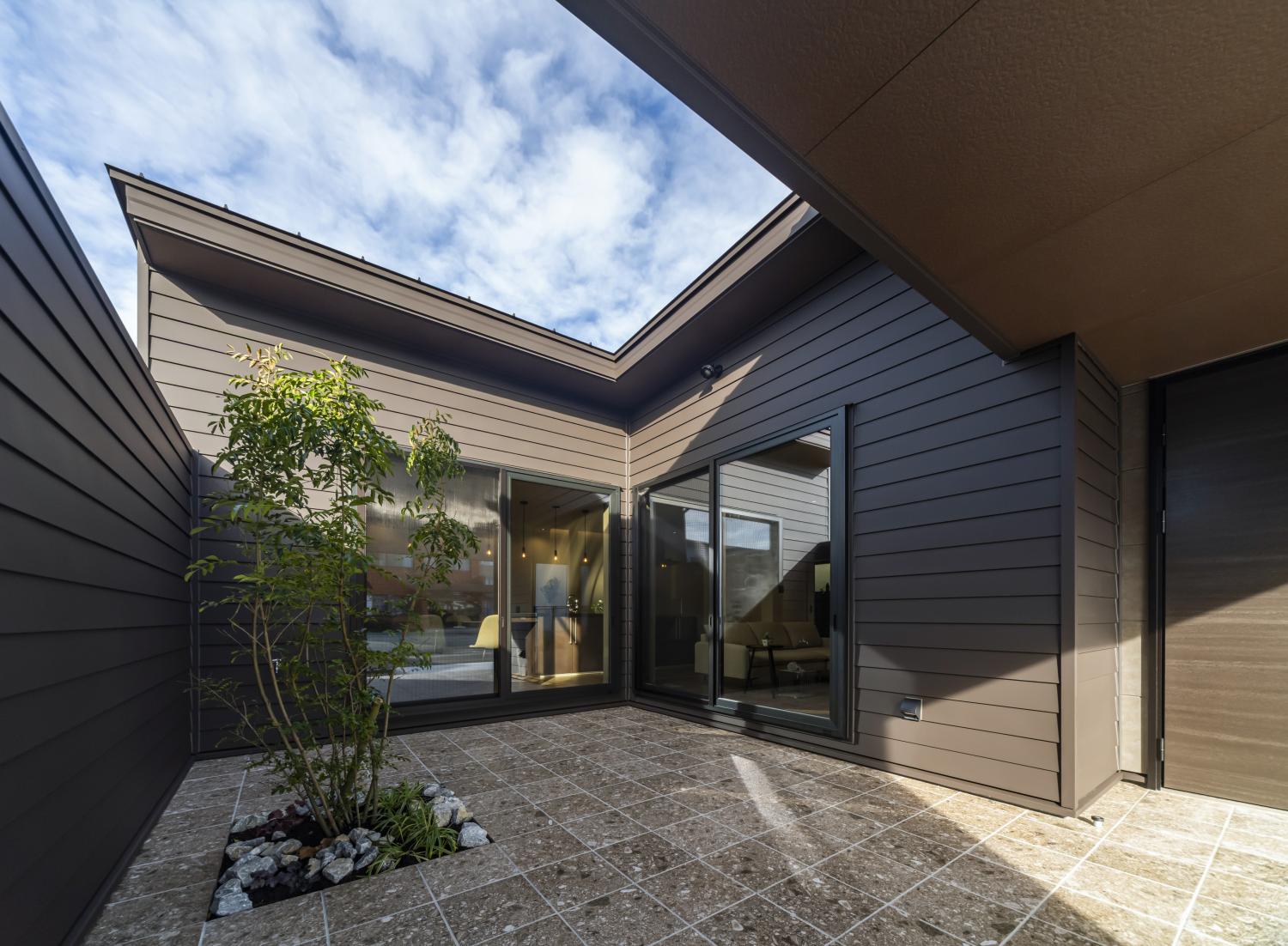 エントランスとタイルテラスが一体になった空間。半分開放された囲い庭が、プライバシーを守りながらも光と風を贅沢に室内に取り込んでくれる