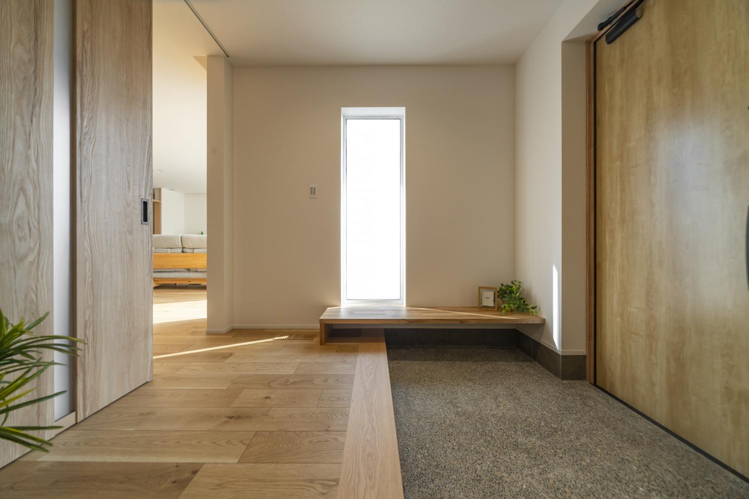 洗い出しの土間と木のベンチが迎える、やさしい設えの玄関